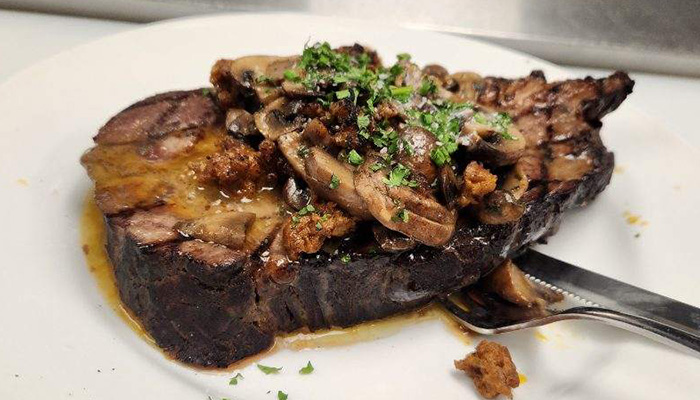 Ribeye topped with mushrooms prepared by The Chartroom at River's End Restaurants in Racine, Wisconsin.